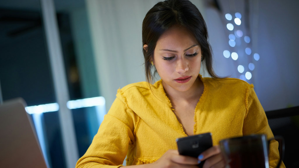 WhatsApp condomínio - mulher concentrada analisando mensagens no celular com expressão séria