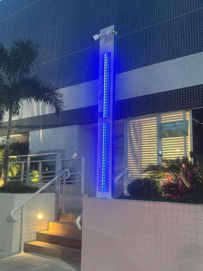 Totem Safer iluminado na entrada de um condomínio à noite